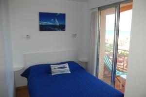 a bedroom with a blue bed and a balcony at Appartement Belle Vue in Valras-Plage