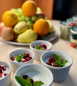 a table topped with bowls of fruit with raspberries and mint at Hotel Rustikal in Horní Cerekev