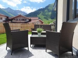 um pátio com cadeiras e uma mesa com um vaso de plantas em Alpenflair em Berwang