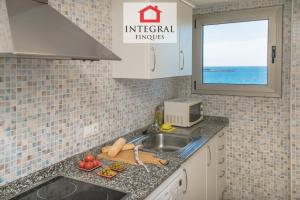 a kitchen with a sink and a microwave and a window at La Vela Apartment in Palamós