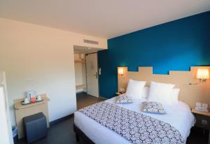 a bedroom with a large bed with a blue wall at Hotel Le Virevent in Saint-Raphaël