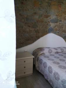 een slaapkamer met een bed en een stenen muur bij La Rosa dei Venti in Cantagrillo