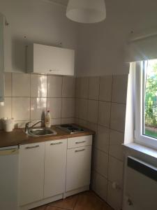 a kitchen with white cabinets and a sink and a window at Dom pod Białym Pagajem in Pisz