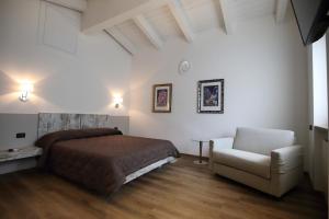 ein Schlafzimmer mit einem Bett und einem weißen Stuhl in der Unterkunft Albergo Antica Locanda in Clusone