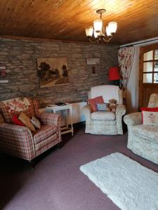 sala de estar con 2 sillas y sofá en Carnowen Cottage en Ringsend