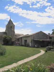 un antiguo edificio con una iglesia y un patio de césped en La Grange, en Vanzay
