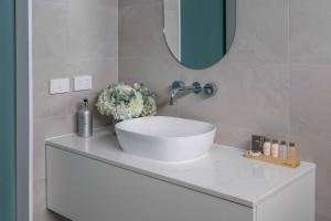 La salle de bains est pourvue d'un lavabo blanc et d'un miroir. dans l'établissement Currajong Retreat, à Burragate