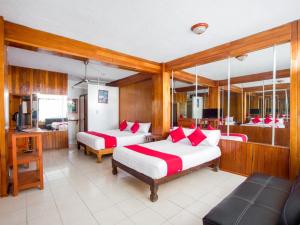 a bedroom with two beds with red and white pillows at Hotel Suites Tropicana Ixtapa in Ixtapa