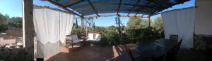 a patio with white curtains and a table and chairs at Arcamyrtus in Alghero