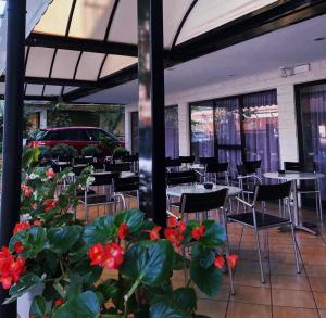 un restaurante con mesas, sillas y flores rojas en Hotel Susy en Rímini