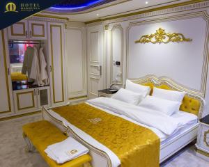 ein Schlafzimmer mit einem großen Bett und einer gelben Bank in der Unterkunft Hotel Mamounia Boutique in Pristina