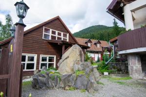 ein Holzhaus mit einem Felsen davor in der Unterkunft Pension Csomád in Băile Tuşnad