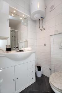 a white bathroom with a sink and a toilet at Apartments ITD in Trogir