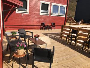eine Terrasse mit Stühlen und Tischen sowie ein rotes Gebäude in der Unterkunft Haugen Pensjonat Svalbard in Longyearbyen
