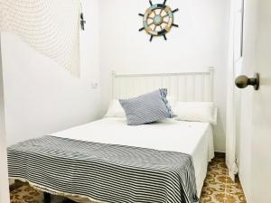 a white bedroom with a bed and a clock on the wall at Casita Marinera in Peniscola