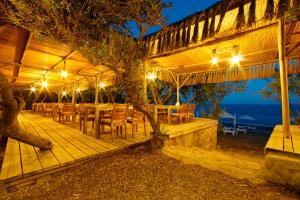 una terraza de madera con mesas y sillas por la noche en Ova Butik Otel, en Mesudiye