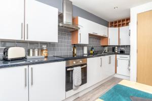 a kitchen with white cabinets and a counter top at Historic Location, Private Parking, Ground Floor Luxury Flat in Aberdeen