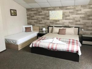 a bedroom with two beds and a brick wall at Guest House Urdoviza in Kiten