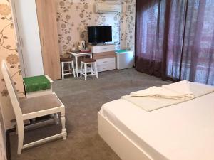 a room with two beds and a chair and a television at Guest House Urdoviza in Kiten