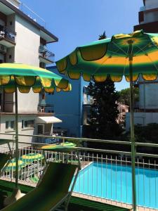 een zwembad met een glijbaan en parasols naast een gebouw bij Hotel Susy in Rimini