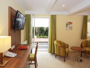 ein Hotelzimmer mit einem Schreibtisch und einem Tisch mit einem TV in der Unterkunft Hotel Goldener Adler in Linz