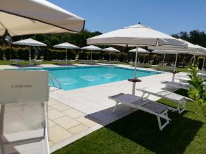 una piscina con sombrillas y sillas, una mesa y sillas y una piscina en Masseria Carrozzi en Melendugno