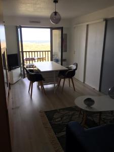 een woonkamer met een tafel en stoelen en een balkon bij Face à la mer à Cabourg in Cabourg