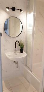 W białej łazience znajduje się umywalka i lustro. w obiekcie Pokoje Gościnne Muszelka 300 m do plaży w mieście Mielno