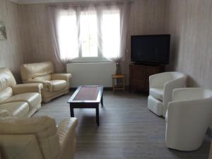 a living room with white furniture and a flat screen tv at maison de vacances in Grandcamp-Maisy