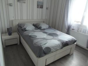 um quarto com uma cama com um edredão branco e preto em maison de vacances em Grandcamp-Maisy