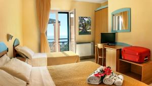 una camera d'albergo con due letti e una televisione di Hotel Alizé a Santa Cesarea Terme
