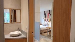 een badkamer met een wastafel en een kamer met een bed bij Hôtel The Originals Résidence de Rohan (EX RELAIS DU SILENCE) in Vaux-sur-Mer