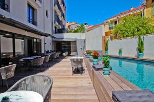un patio avec des tables et des chaises à côté d'une piscine dans l'établissement Hôtel La Villa Port d'Antibes & Spa, à Antibes