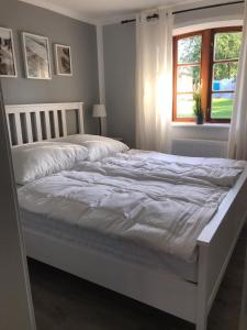 ein weißes Bett in einem Schlafzimmer mit einem Fenster in der Unterkunft Ferienwohnung Familie Manthei in Boitin Resdorf