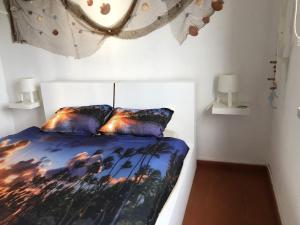 a bedroom with a bed with a painting on it at Fonte da Telha Beach Hostel in Costa da Caparica