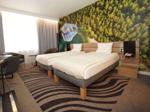 a hotel room with two beds and a painting on the wall at Novotel Vilnius Centre in Vilnius