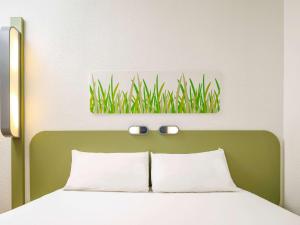 a bed with a green headboard with a picture of grass at ibis budget Cardiff Centre in Cardiff