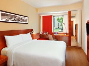 um quarto com uma cama branca, uma secretária e uma janela em ibis New Delhi Aerocity - An Accor Brand em Nova Deli