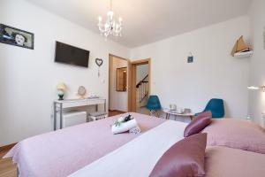 a bedroom with a large bed with pink sheets and purple pillows at Rooms Antonio in Trogir