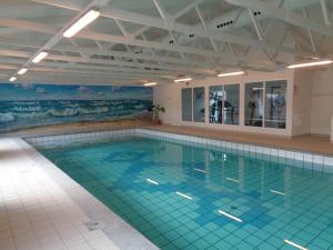 a swimming pool in a building with a large swimming pool at Hotel Tannishus in Bindslev