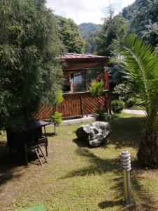 a cabin in a garden with a bench and a tree at Vacation Home Nukri in Gonio