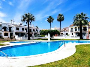 a swimming pool in front of a house with palm trees at Bungalow con vistas a la piscina in Torrevieja