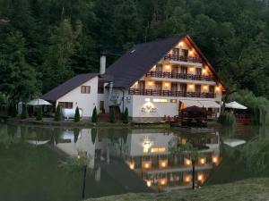 a large house with lights on the water at night at Guest house Lacul Linistit in Moneasa