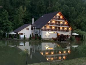 una casa grande con luces en el agua por la noche en Guest house Lacul Linistit en Moneasa