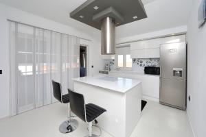 cocina blanca con encimera blanca y sillas en Apartments Neli, en Bibinje