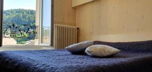 a bed with a pillow on it with a window at Hôtel Saint Jean in Vals-les-Bains