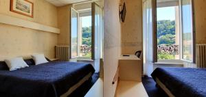 a bedroom with two beds and a window at Hôtel Saint Jean in Vals-les-Bains