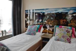a bedroom with two beds and a painting on the wall at Stasjonen Hotel Lillehammer in Lillehammer