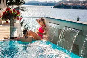 un hombre y una mujer sentados en una piscina en Hotel Eden en Podstrana