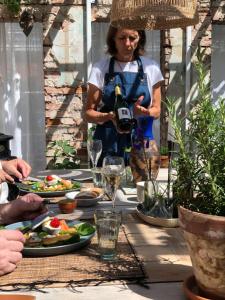 a woman holding a bottle of wine at a table with food at Havings skafferi in Lysekil